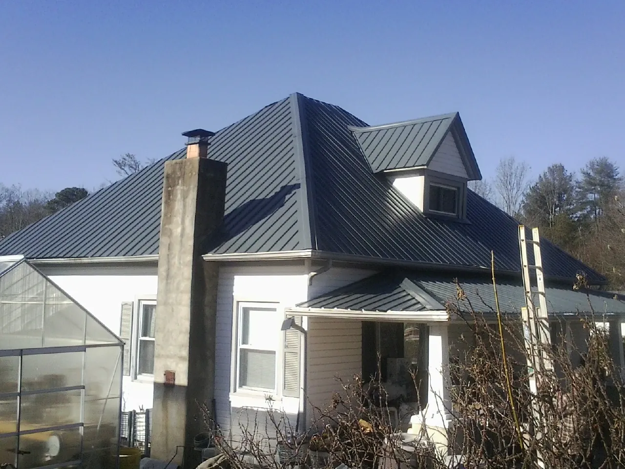 Dark blue standing seam metal roof on a white farmhouse with dormer in Fairfield