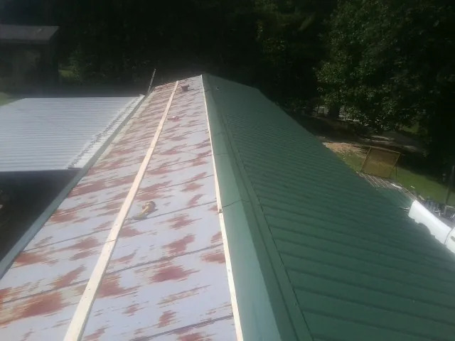 Old rusted panels beside newly installed green metal roofing — Wind Damage Roof Repair by Roofing Brothers in Fairfield