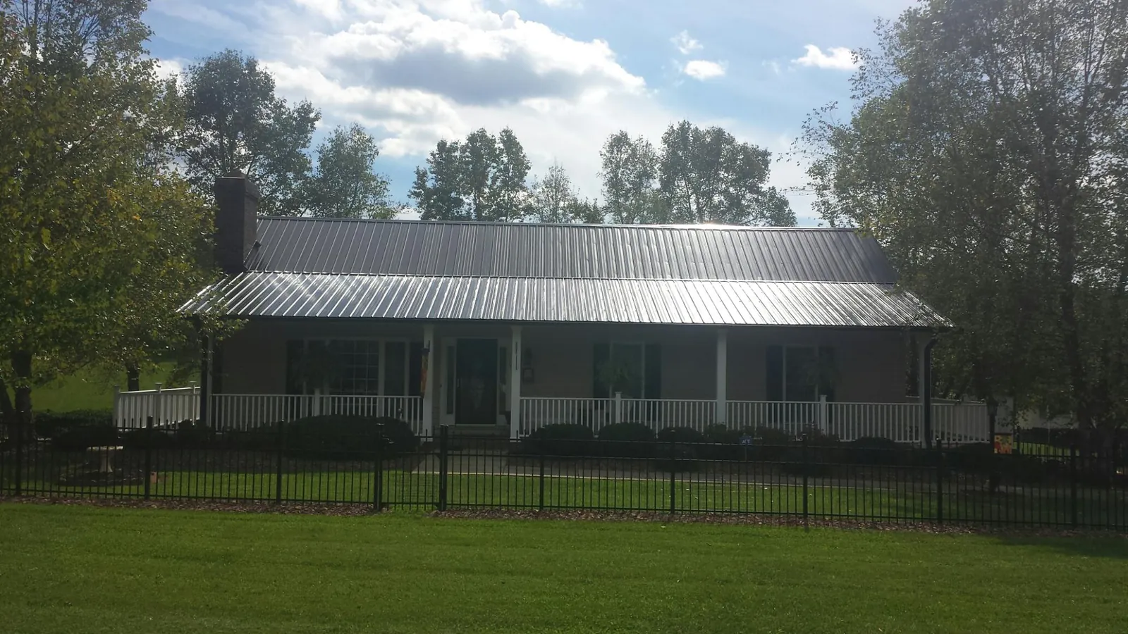 Gray metal roof on a brick ranch with a full width front porch — Gutter Guard Installation work by our crew in Fairfield